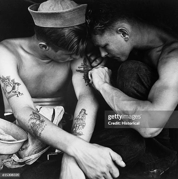 Sailor aboard the U.S.S. New Jersey inspects another sailor's tattoos. December 1944. | Location: aboard the U.S.S. New Jersey, Pacific Ocean.