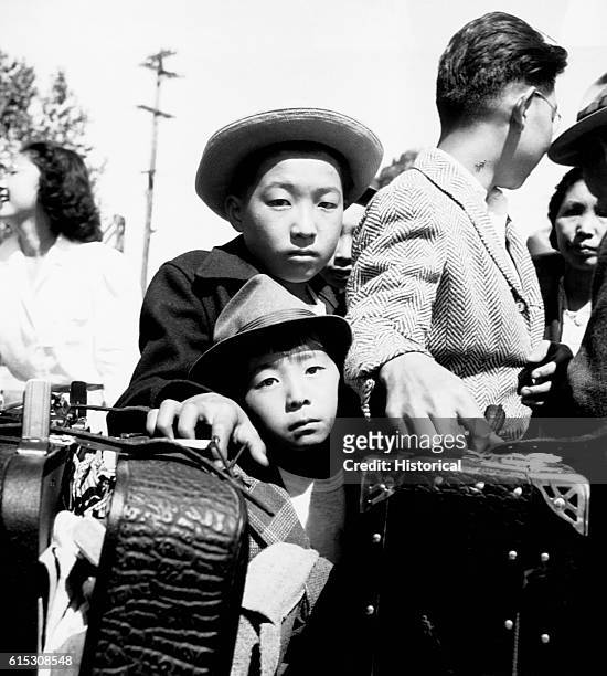 Young evacuees of Japanese ancestry are awaiting their turn for baggage inspection upon arrival at a World War II Assembly Center in Turlock, CA....