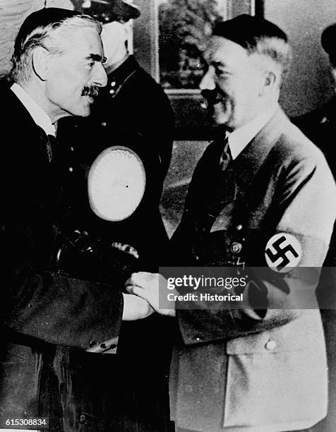 British Prime Minister Neville Chamberlain and German Fuehrer Adolf Hitler shake hands in this composite photograph at the 1938 Munich Conference in...