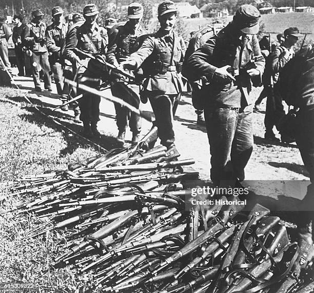 German soldiers surrendering at the Danish-German border, throwing their firearms in a pile as they file by. | Location: Border of Denmark and...