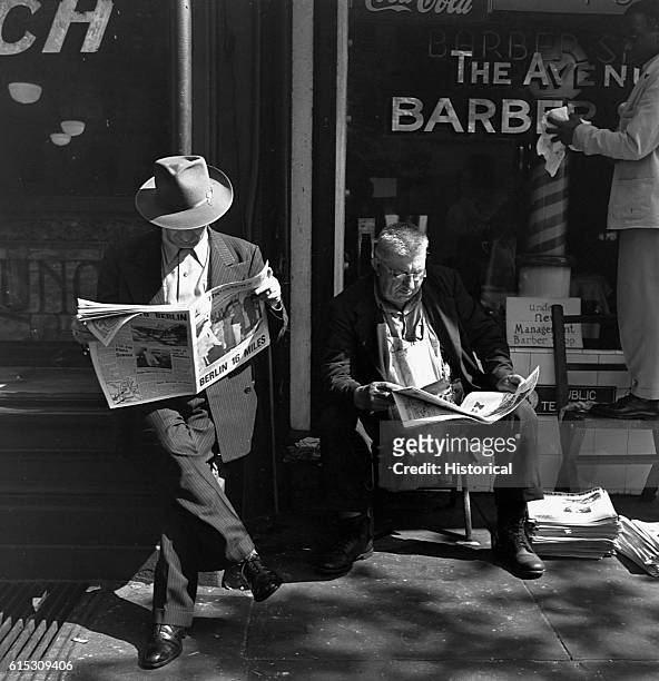 Two men read the announcements of President Franklin D. Roosevelt's death in front of The Avenue Barber Shop in Washington, D.C. April 14, 1945.