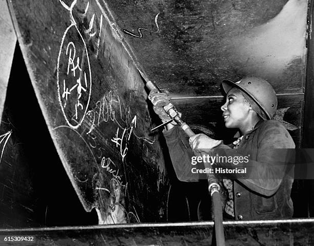 Miss Eastine Cowner, a former waitress, works as a scaler at the Kaiser Shipyards. Here she is helping to construct the Liberty Ship SS George...