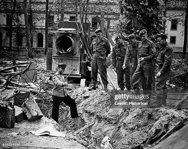 Russian soldier shows newly arrived British "Tommies" where the Russians found the bodies of Adolf and Eva Hitler. Berlin, May 1945.