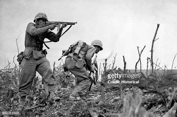 As his companion ducks for cover, a U.S. Marine aims his sub-machine gun at a Japanese sniper at Wana Ridge before the town of Shuri on South...