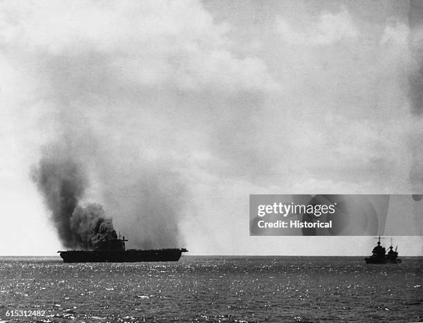 The Yorktown was damaged heavily by Japanese aircraft June 4, 1942 in the Battle of Midway. Escort ships hover near the damaged carrier which went to...