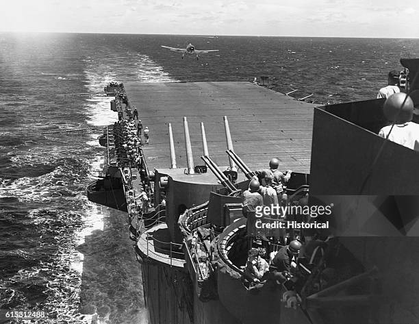 Guns manned and ready as a F6F fighter aircraft lands on the flight deck of the USS Lexington during the Japanese air attack on task force 58 in the...