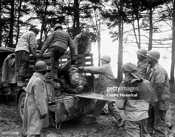 Men of the 3201 Quartermaster Service Company load U.S. Casualties from the U.S. 3rd Army front on a truck for burial at the U.S. Military Cemetery....