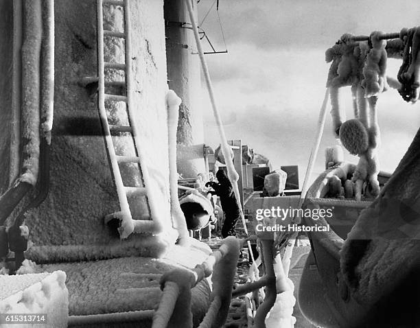 Crew member keeps a tight grip on the side of a torpedo tube in an effort to stay upright on the ice-encrusted deck of a U.S. Destroyer World War II....