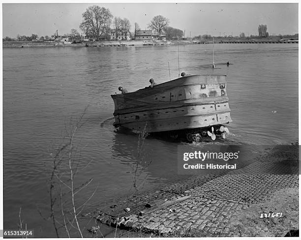 American soldiers of the 748th Tank Battalion cross the Rhine River with an amphibious tank outfitted with air inflated sides and two propellers....