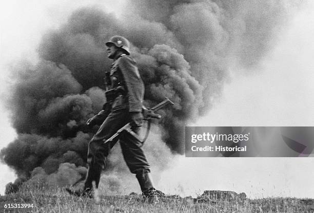 German assault troop leader strides past exploding ammunition during the German invasion of Russia, 1941.