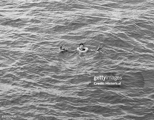 Survivor of U-175, a life ring around his neck, treads water and gestures for help while awaiting rescue. Atlantic Ocean.