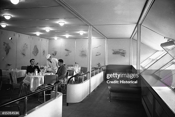 Passengers dine comfortably in the luxurious dining area of the Hindenburg dirigible during the 1930s. | Location: inside airship.