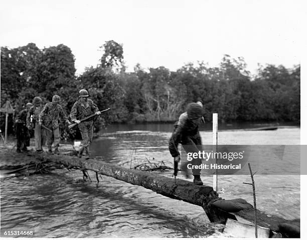 Marine patrol crosses a river to get at Japanese snipers ahead.