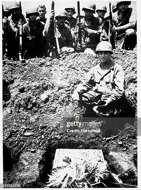 Infantrymen kneel as their chaplain reads the final benediction for Ernie Pyle, the popular American war correspondent, on April 20, 1945. Pyle was...