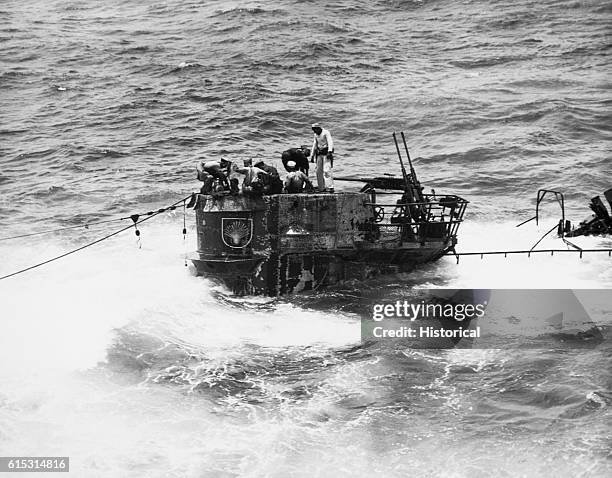 Members of a boarding party from the USS Guadalcanal descend through the hatch of a captured German U-boat.