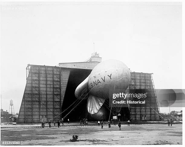 Ground crew members pull an Italian kite balloon from its hangar at the Naval Air Station in Pensacola, Florida. March 19, 1920 | Location: Naval Air...