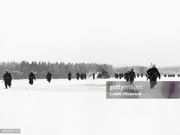 American troops of the 84th Infantry Division advance through a snowfield in France towards La Roche, Belgium during the Battle of the Bulge. January...