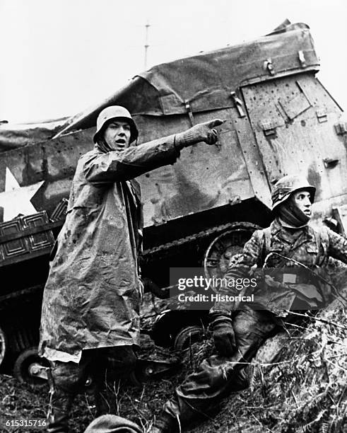 German soldiers take cover in a ditch beside a disabled American tank during the Battle of the Bulge. Belgium, December 1944.
