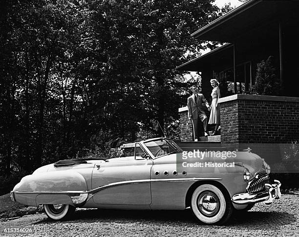 Happy couple with a house and a new 1949 Buick Roadmaster - the pinnacle of luxury and prosperity in a postwar lifestyle.