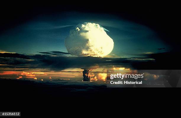 Billowing white mushroom cloud, mottled with orange, pushes through a layer of clouds during Operation Ivy, the first test of a hydrogen bomb, at...