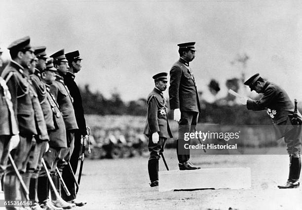 Emperor Hirohito of Japan receives a bow from the leader of a military unit during a troop review during World War II.