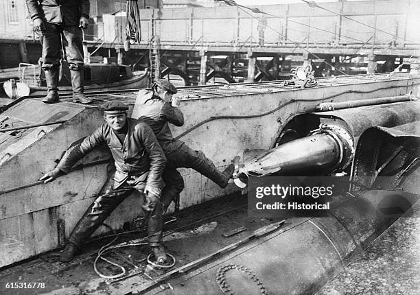 Two sailors push a torpedo into the topedo tube of a U-boat docked in Germany during World War One.