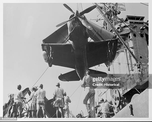 First Indochina War, 1945-55. American involvement. At the docks, a US-made light bomber is swung from the decks of the USS Cape Esperance as part of...