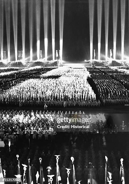 Massive searchlight beams surround the stadium in Nuremberg, Germany during one of Hitler's rallies in support of the Nazi party. 1936