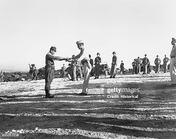 Japanese Imperial Army Captain Sakae Oba surrenders his samurai sword to Lt. Col. Howard Kurgis at Saipan on December 1, 1945. Oba and 46 other...