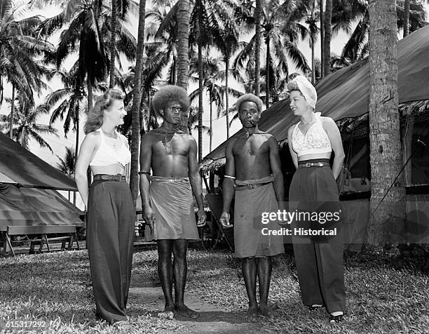 Two women who are members of Bob Hope's troupe stand beside native men of the South Pacific, 1944.