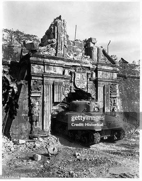 Tanks enter through the historic gate of old Fort Santiago, which was damaged by shells when troops stormed Manila.