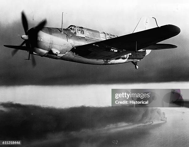 An SB2c flies over a Japanese convoy burning in Cam Ranh Bay after attack by planes from the USS Hancock. January 12, 1945