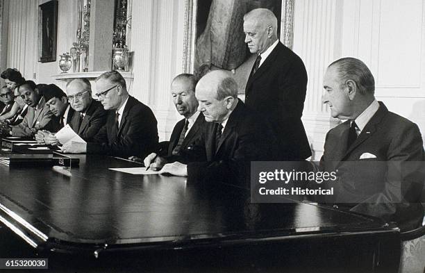 President Johnson looks on as Secretary of State Dean Rusk signs the treaty for the Non-Proliferation of Nuclear Weapons.