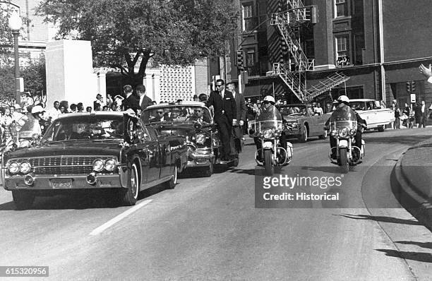 John F. Kennedy's motorcade passes the Texas School Book Depository prior to the assassination on November 22, 1963 in Dallas, Texas.