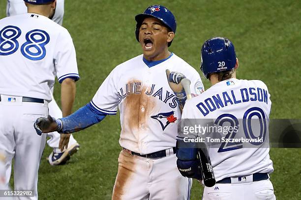 Ezequiel Carrera of the Toronto Blue Jays celebrates with teammate Josh Donaldson after scoring a run off of a grounded out single hit by Ryan Goins...