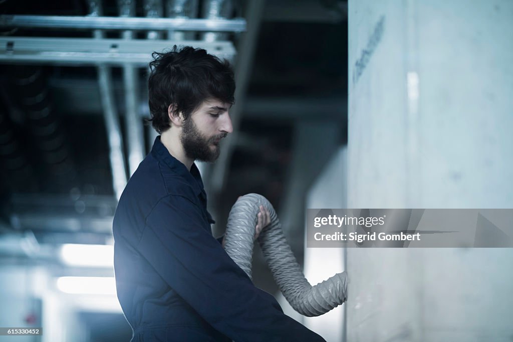 Young male engineer checking hose connection in an industrial plant, Freiburg im Breisgau, Baden-Württemberg, Germany
