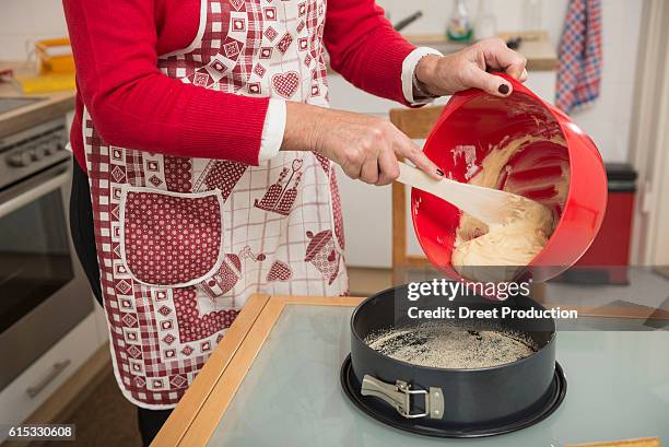 senior woman pouring dough into a spring form pan, munich, bavaria, germany - ausbackteig stock-fotos und bilder