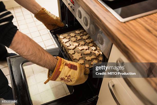 close-up of a man taking out baked cookies from the oven, munich, bavaria, germany - sugar cookie stock pictures, royalty-free photos & images