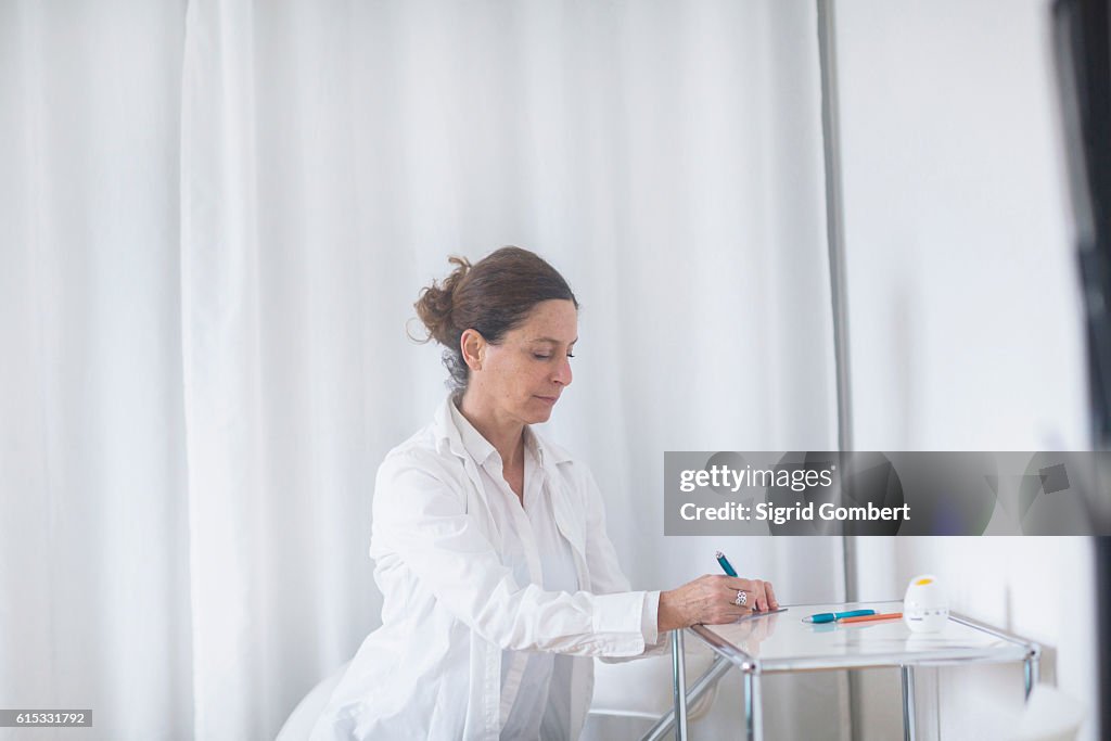 Female doctor writing prescription in hospital, Freiburg im Breisgau, Baden-Württemberg, Germany