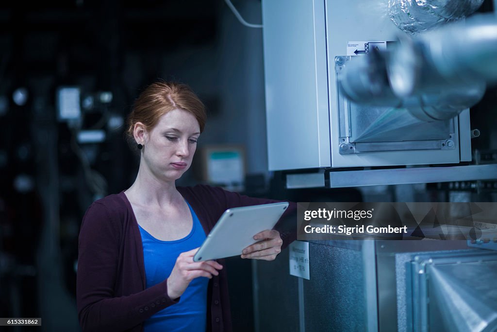 Young female engineer using a digital tablet in an industrial plant, Freiburg im Breisgau, Baden-Württemberg, Germany