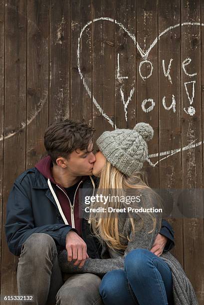 young couple kissing with a drawn heart and love you written on a wooden wall, munich, bavaria, germany - bavaria girl stockfoto's en -beelden