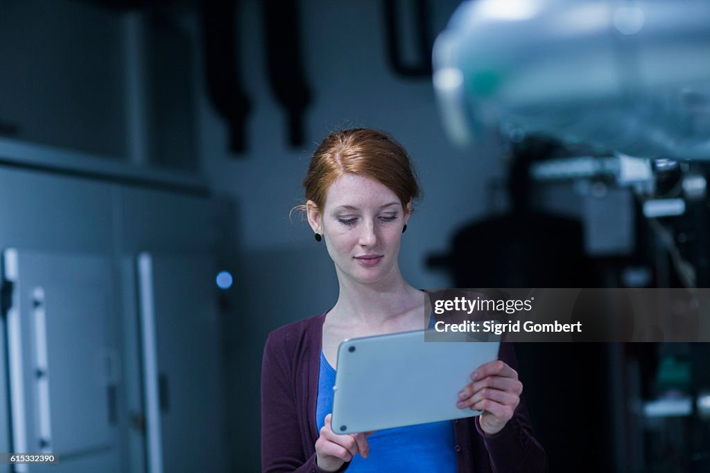 Young female engineer using a digital tablet in an industrial plant, Freiburg im Breisgau, Baden-Württemberg, Germany
