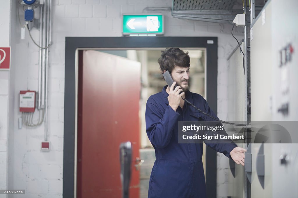 Young male engineer talking on landline phone in an industrial plant, Freiburg im Breisgau, Baden-Württemberg, Germany