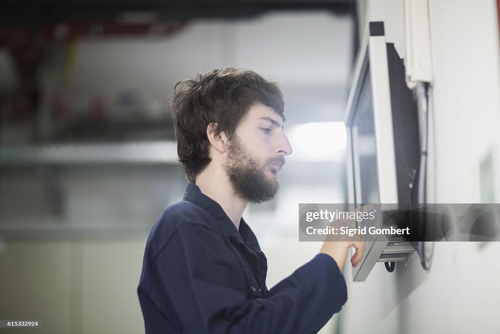 Young male engineer working on touchscreen computer monitor in an industrial plant, Freiburg im Breisgau, Baden-Württemberg, Germany