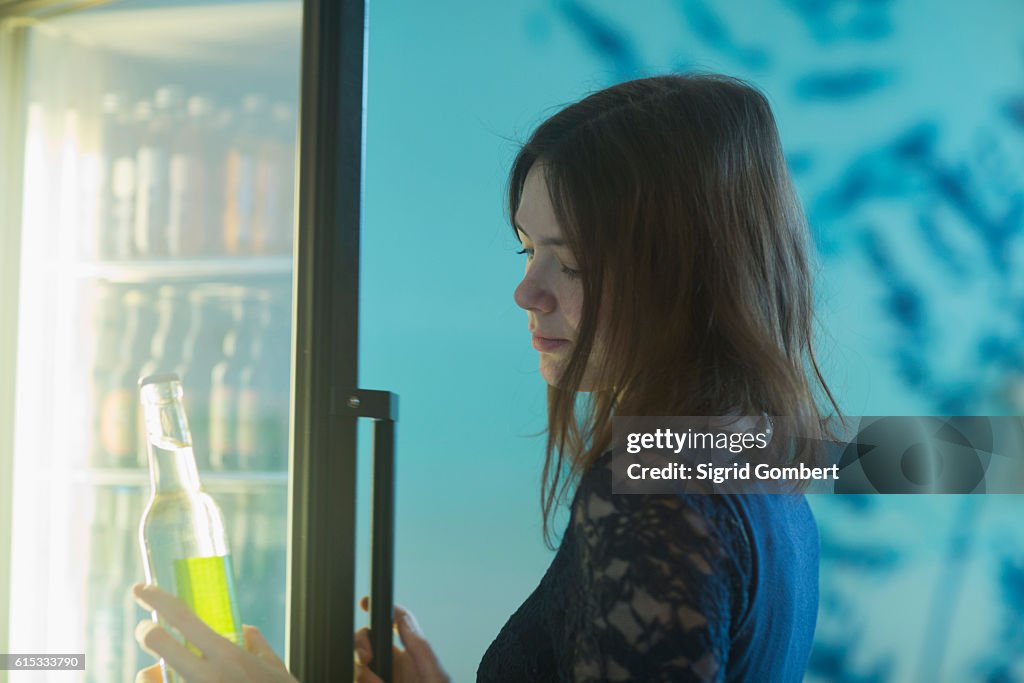 Young woman taking a soda bottle out of refrigerator, Freiburg Im Breisgau, Baden-Württemberg, Germany