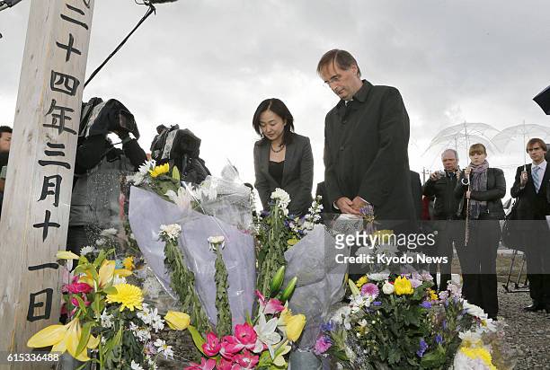 Japan - Dieter Flury , a member of the Vienna Philharmonic, bows his head after offering flowers at a monument honoring victims on Mt. Hiyori in...