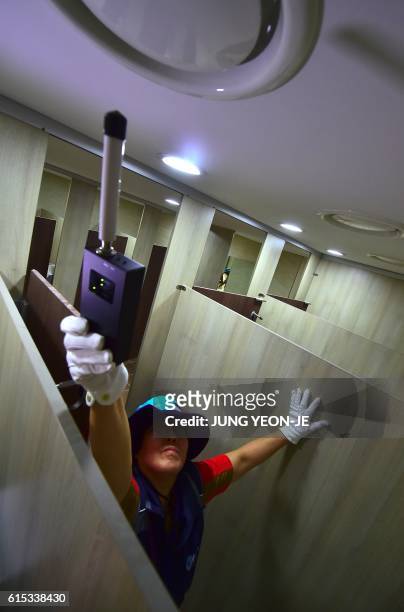 This picture taken on August 18, 2016 shows a member of Seoul city's "hidden camera-hunting" squad waving a hand-held detector around the ventilation...