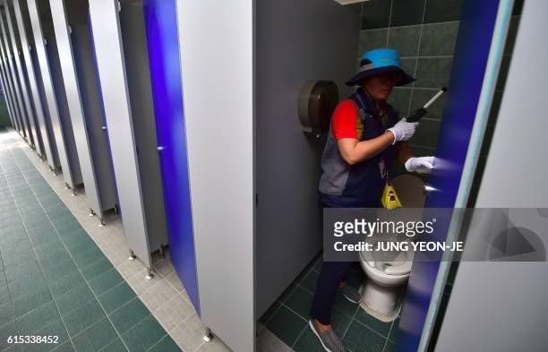 This picture taken on August 18, 2016 shows a member of Seoul city's "hidden camera-hunting" squad inspecting a women's bathroom stall to find...
