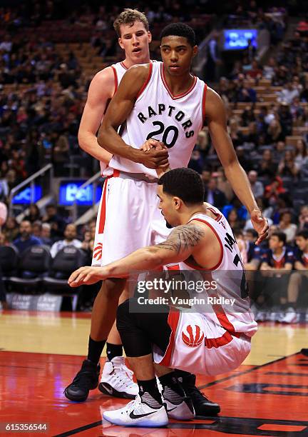 Fred VanVleet of the Toronto Raptors is helped to his feet by Jakob Poeltl and Bruno Caboclo during a NBA preseason game against San Lorenzo de...