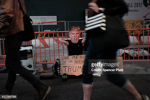 Man asks for tips in Times Square in a Donald Trump mask on October 17, 2016 in New York City. As the nation prepares for the final debate between...